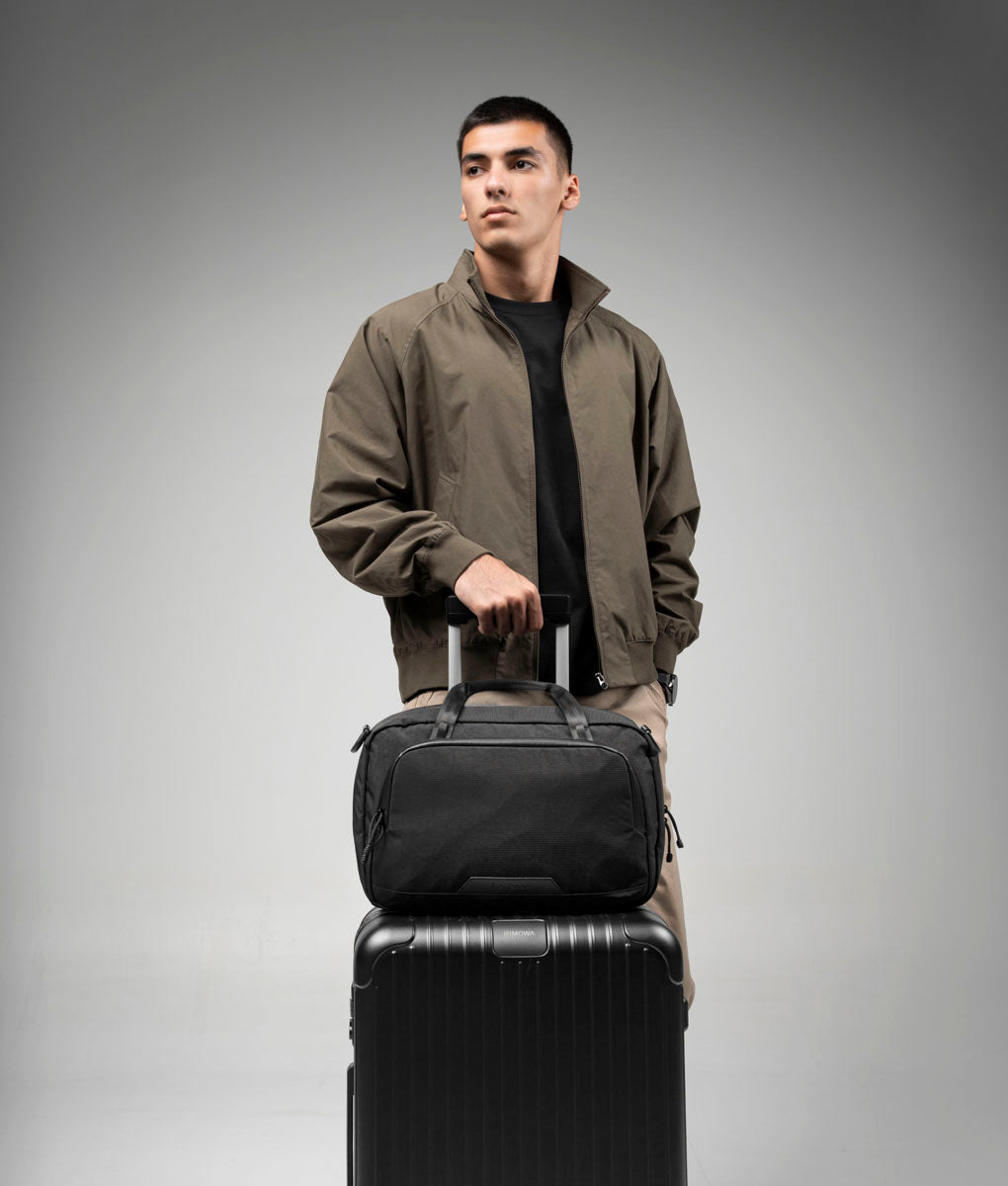 Black Bravo Brief 14 secured over the handle of rolling luggage