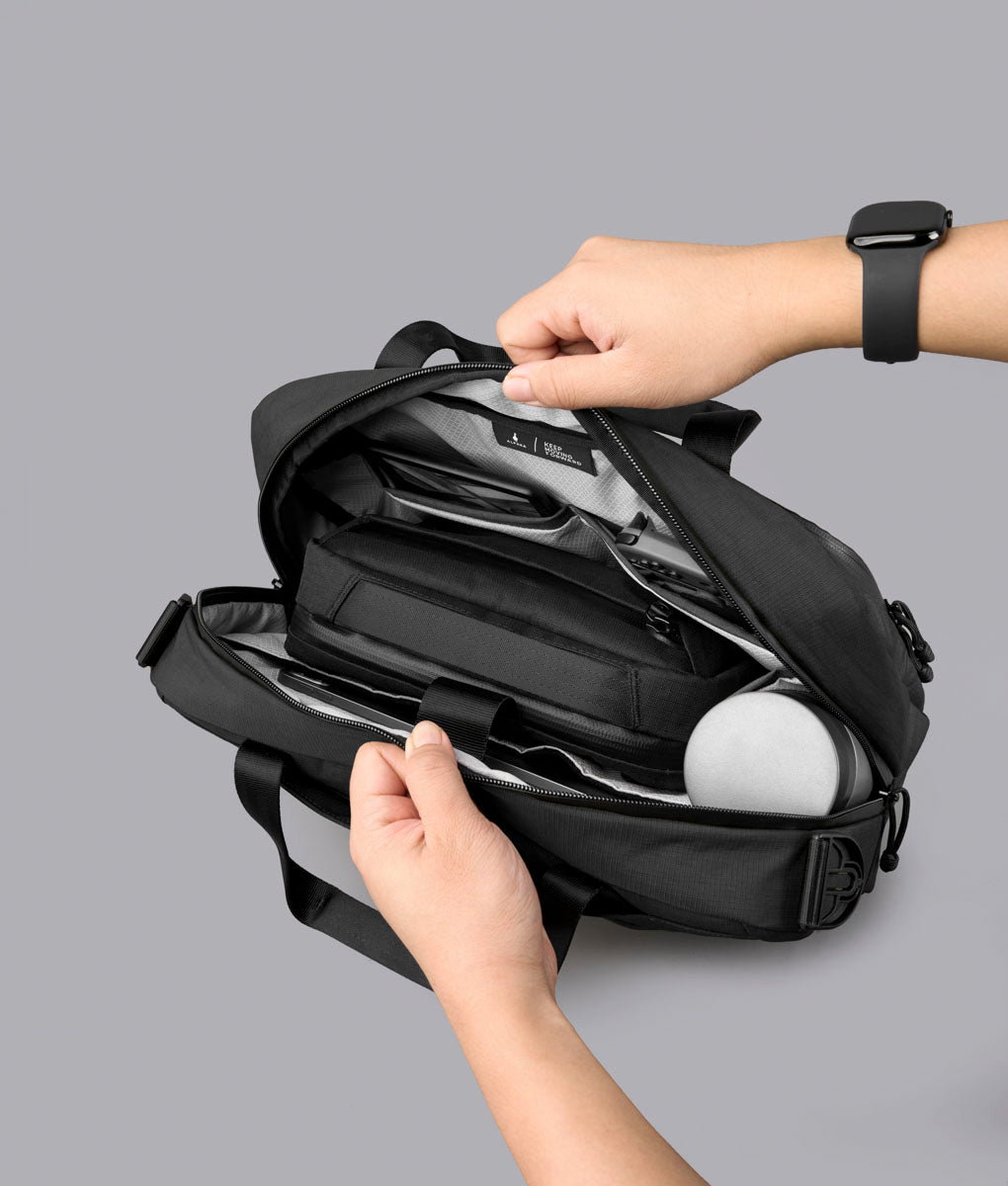 Open black Bravo Brief 14 showing tech and essentials arranged in its compartments