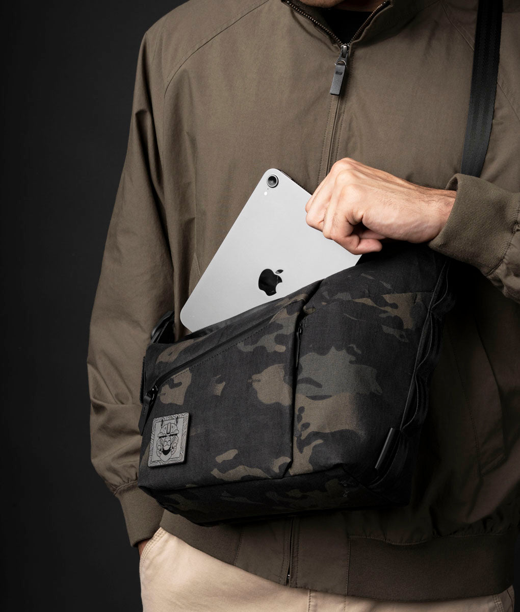An iPad mini sliding into the main compartment of the ClogTwo Edition 4L worn crossbody