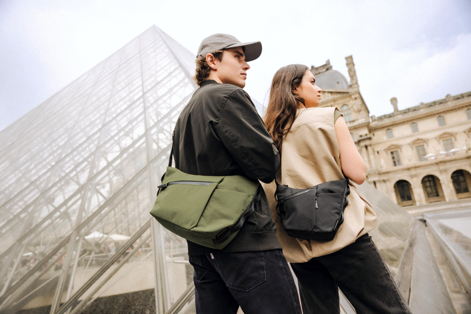 Two people carrying green and black Flow Satchels while walking through the city